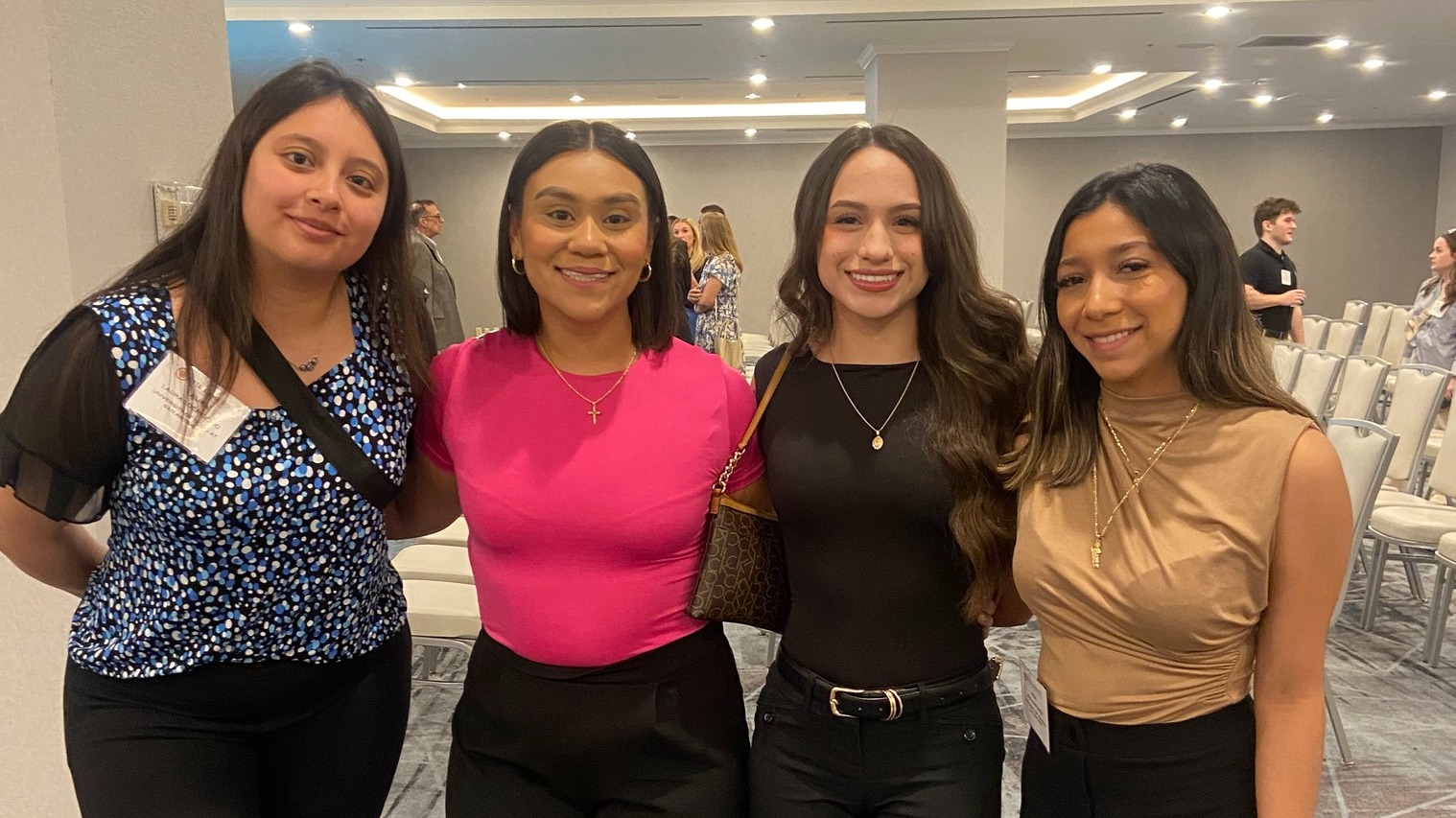 Four women smiling and posing together at a professional event
