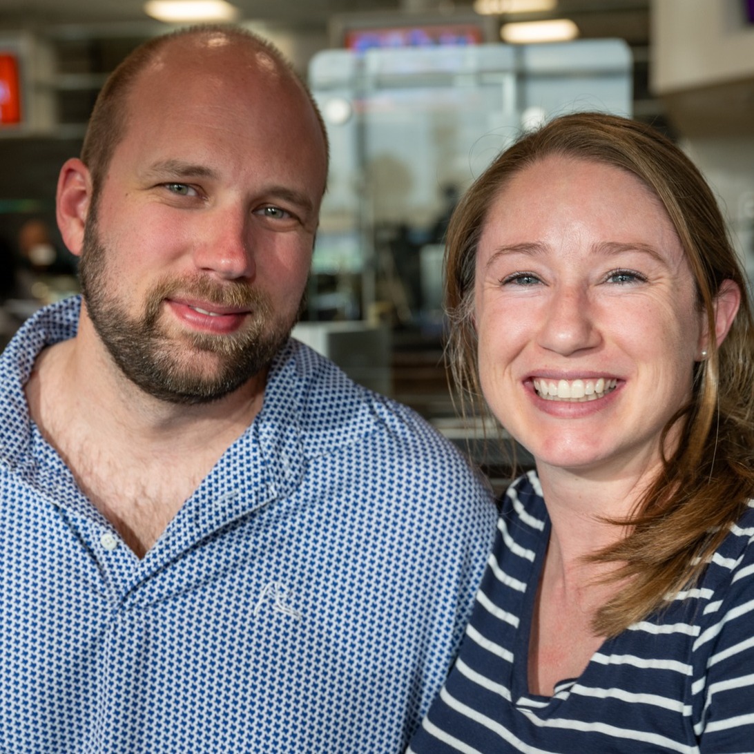 Man and woman smiling while seated indoors at an event or venue