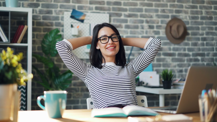 Smiling woman leaning back at her desk in a casual, creative workspace